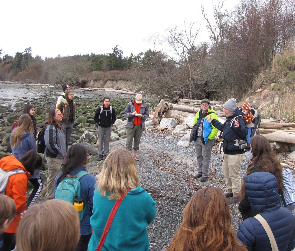 Group of people stand outside on the rocky bed of a river.