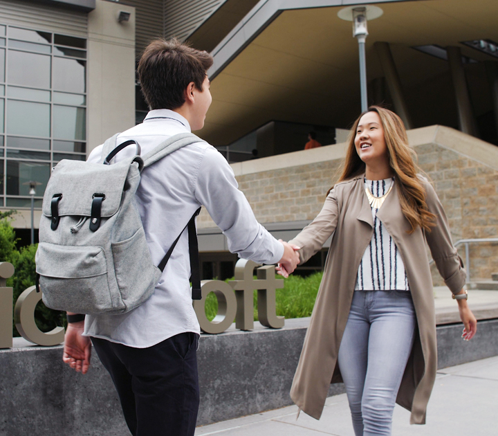 Two people shake hands outside a modern building.