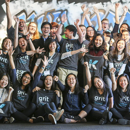 Group of students cheering, all wearing black t-shirts with the word "grit" on them.