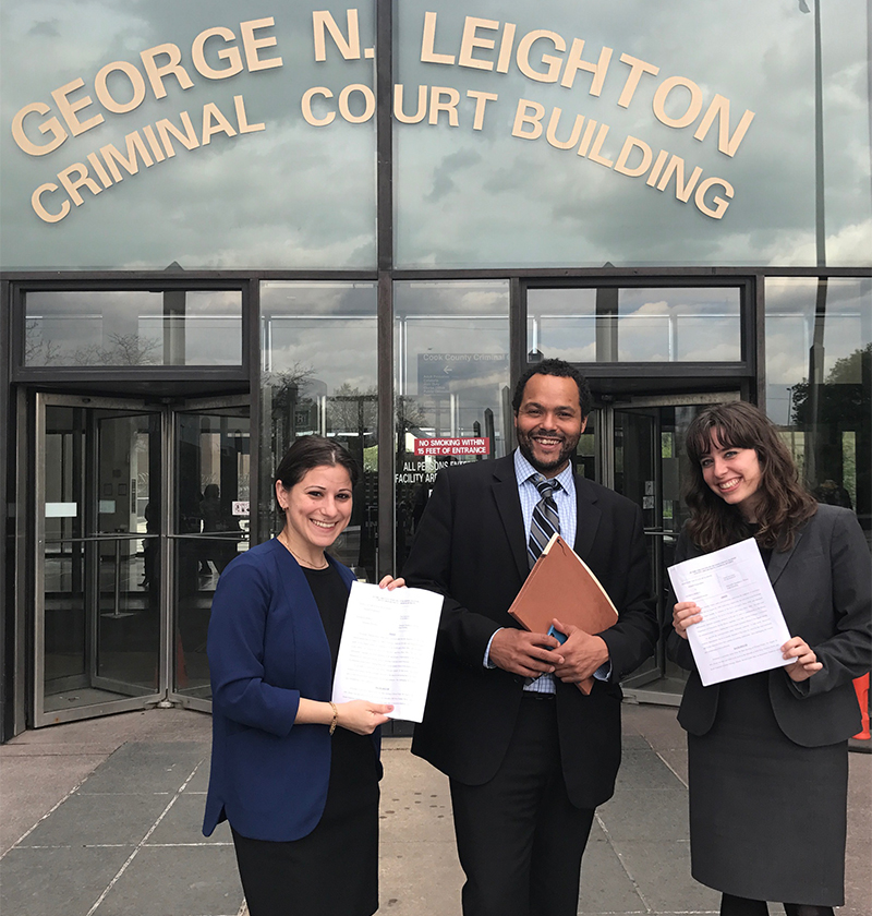 David Owens, standing in the center of two other people, is a philosophy alum and attorney, in front of George N. Leighton Criminal Court Building.