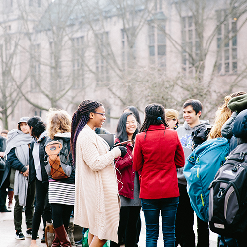 Group of people in colorful coats stand outside and talk to each other.