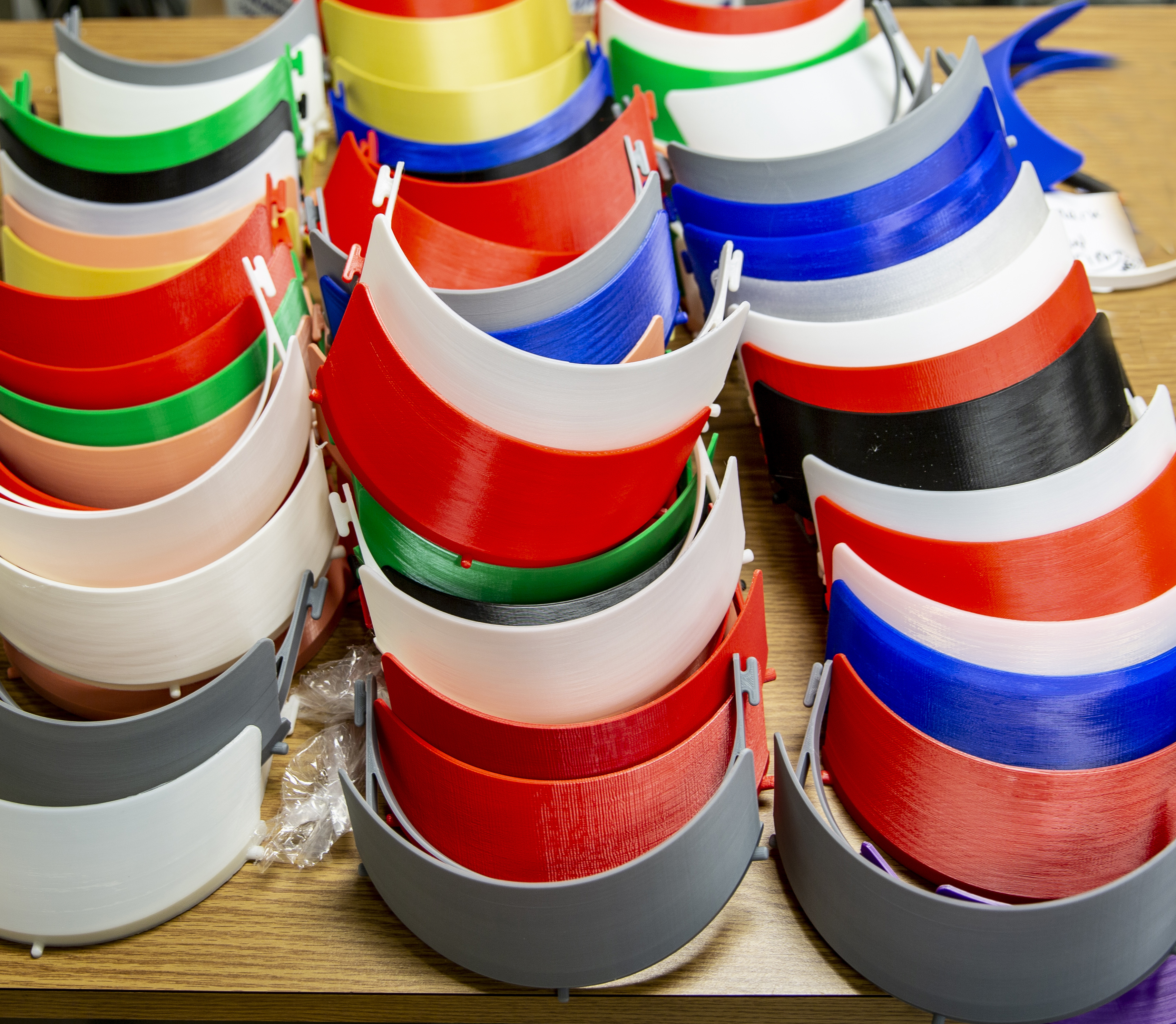 Colorful pile of 3-d printed headbands to be used for face shields.