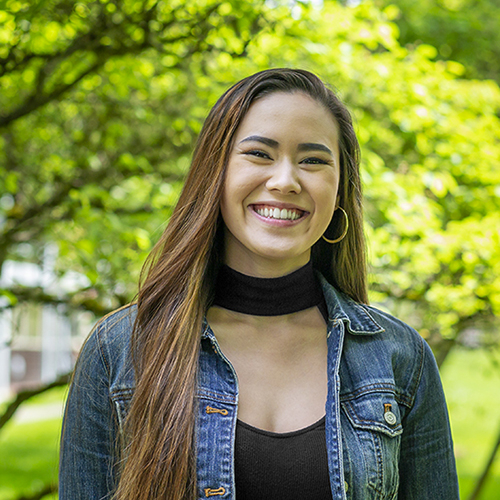 Christine Lew with foliage behind her. 