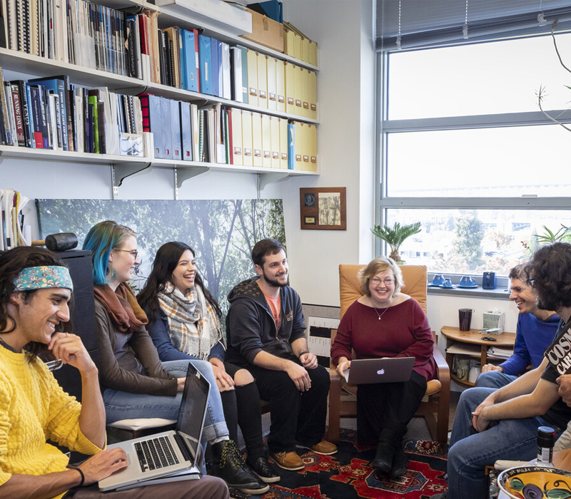 Group of students sitting with female teacher in office