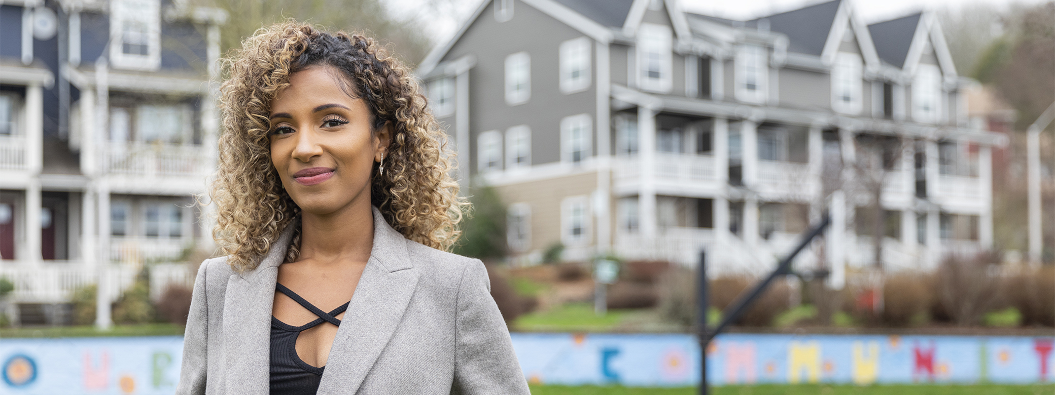 Smiling woman standing in park in front of houses