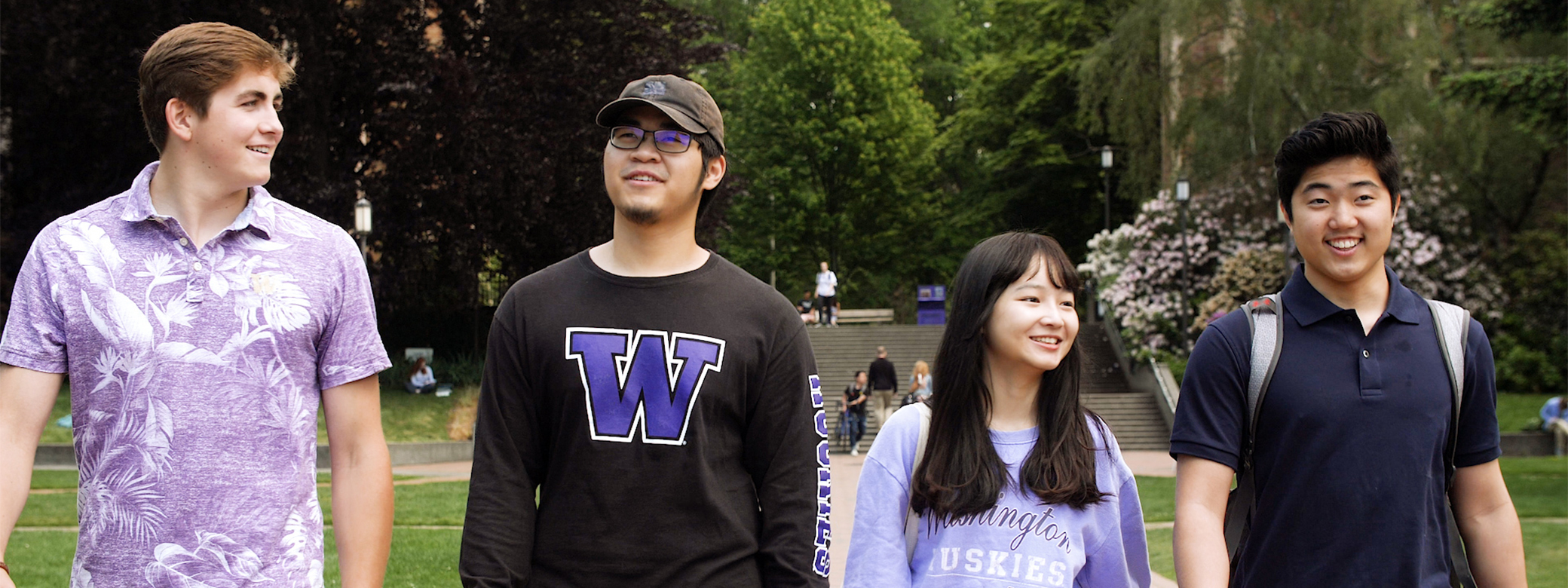 Four students walking in a row together outside