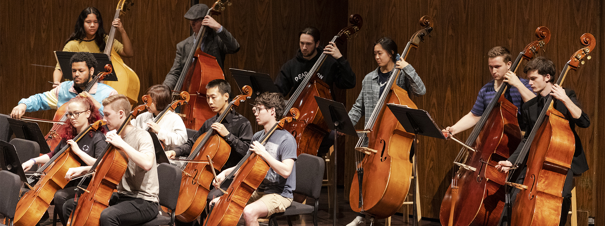 Students in casual attire playing playing string instruments