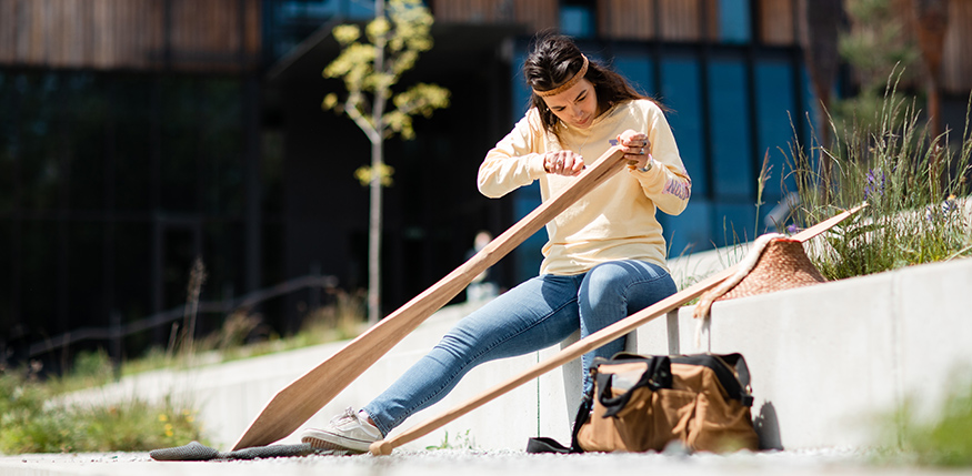 Stephanie Masterman focused on carving the handle of a canoe paddle.