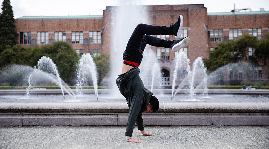 Will Sanchez doing a handstand in front of UW's Drumheller Fountain.