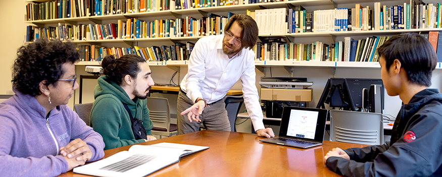 James Davenport with laptop, showing something to the three DiRAC Research Prize students.