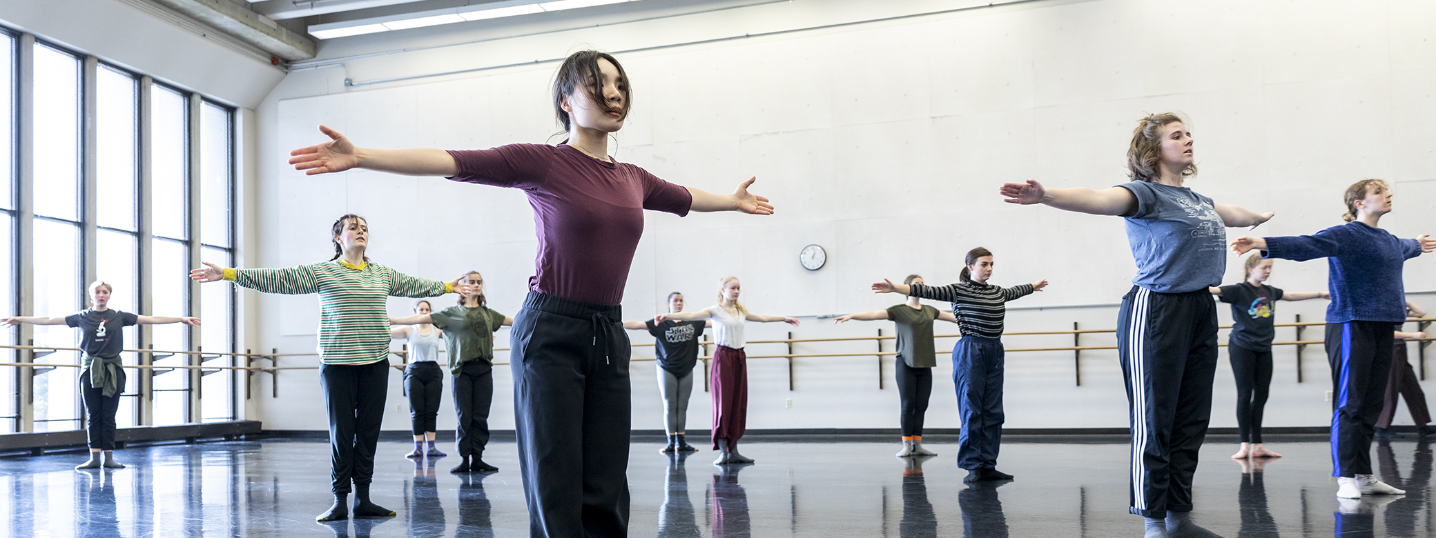 Students in modern dance class, with arms outstretched