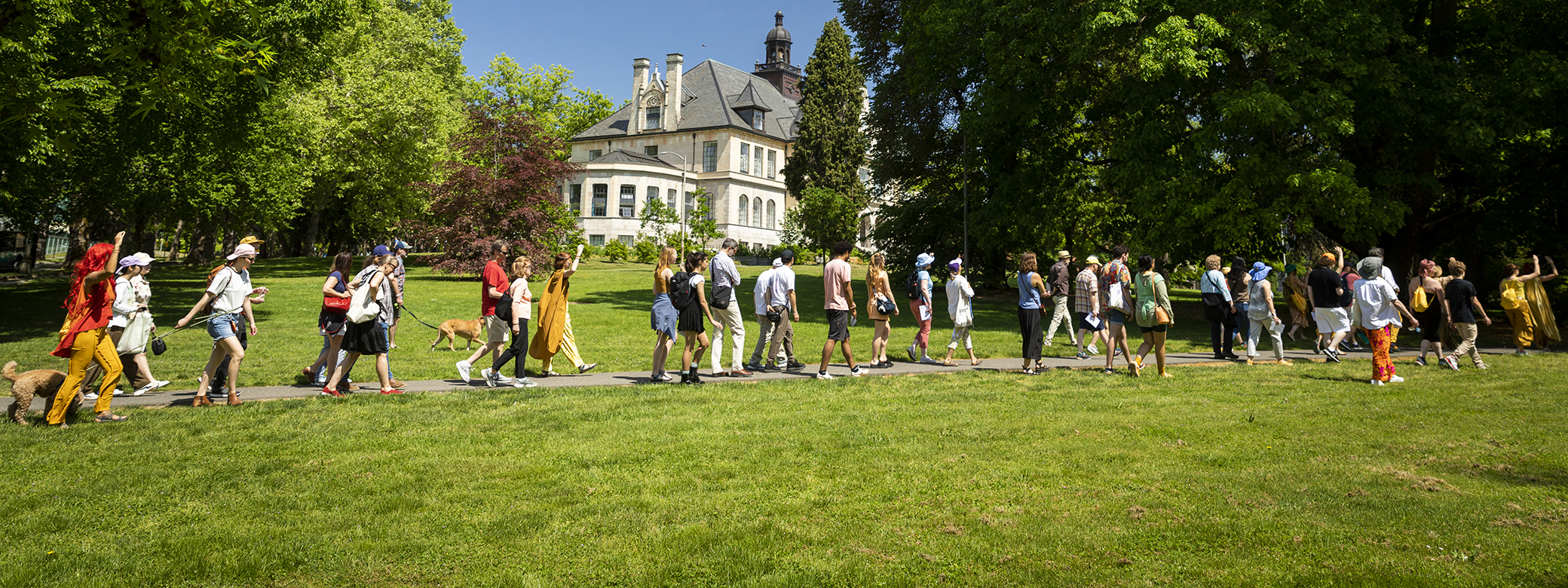 A processional crosses the UW campus, with Denny Hall in the background.