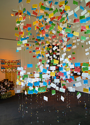 Altar with colorful cards hanging down from ceiling on clear wires. 