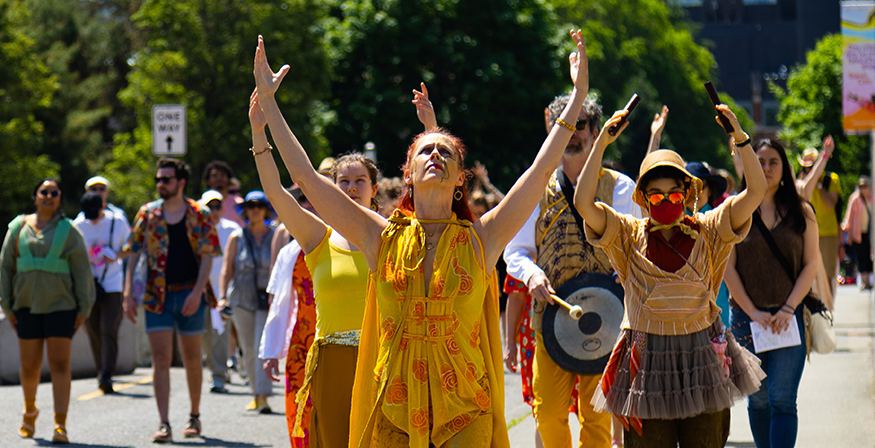 Juliet McMains, with raised arms, leads a procession around the UW campus.