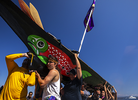 Canoe family members hold the Willapa Spirit high in the air as they lift it out of the water 