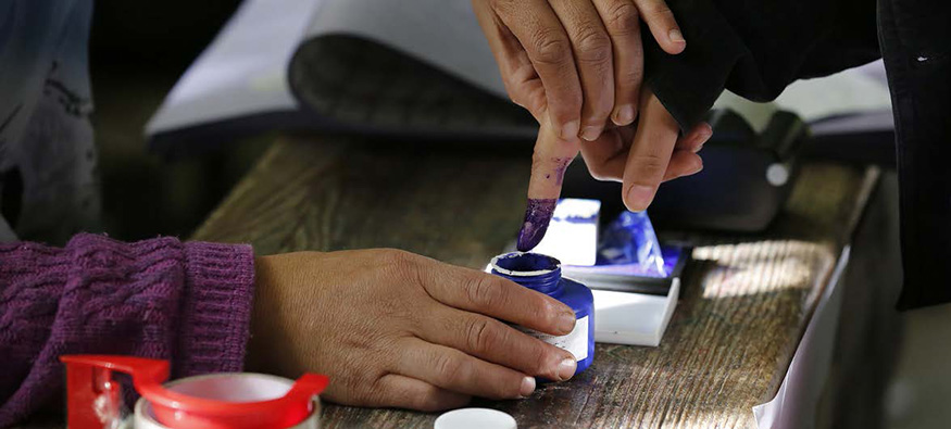 Someone holding a finger up to be marked with ink