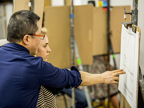 Teacher and student looking at student's drawing in an art studio classroom.