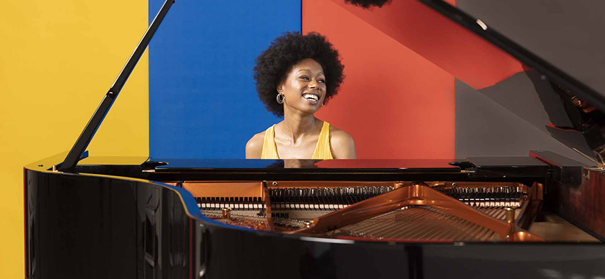 Pianist Isata Anneh-Mason sitting at grand piano. 