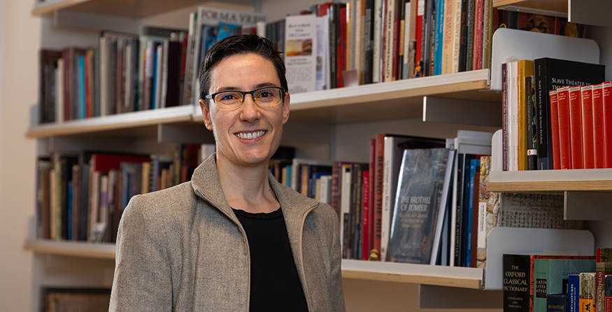 Sarah Levin-Richardson in her office, with books on shelves behind her.