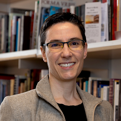 Sarah Levin-Richardson in her office, with books on shelves behind her.