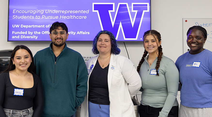 Five people stand in front of a flatscreen displaying a UW Anatomy for Change image.