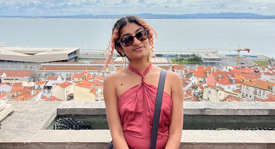 Sana Shetty in Portugal, with red-tiled rooftops in the background.