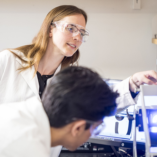 Ashleigh Therberge and research team members looking at equipment in her UW chemistry lab.