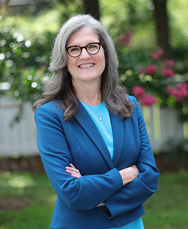 Portrait of Dianne Harris in suit, standing with arms crossed