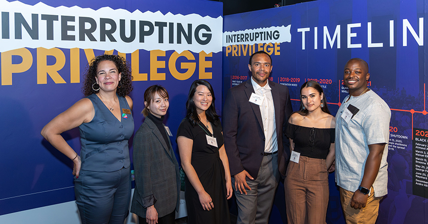 Six members of the Interrupting Privilege team standing in front of the first panel in the Interrupting Privilege exhibit.