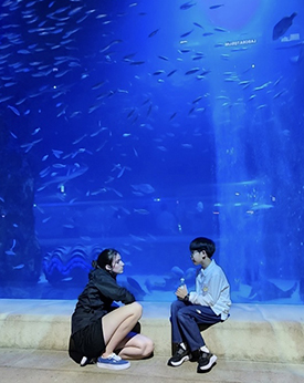 Katie Ruesink sitting with Hojun in front of an exhibit at the aquarium in Seoul.