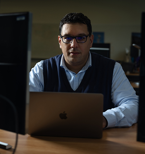 Zaid Harchaoui with open laptop and computers on either side of him.