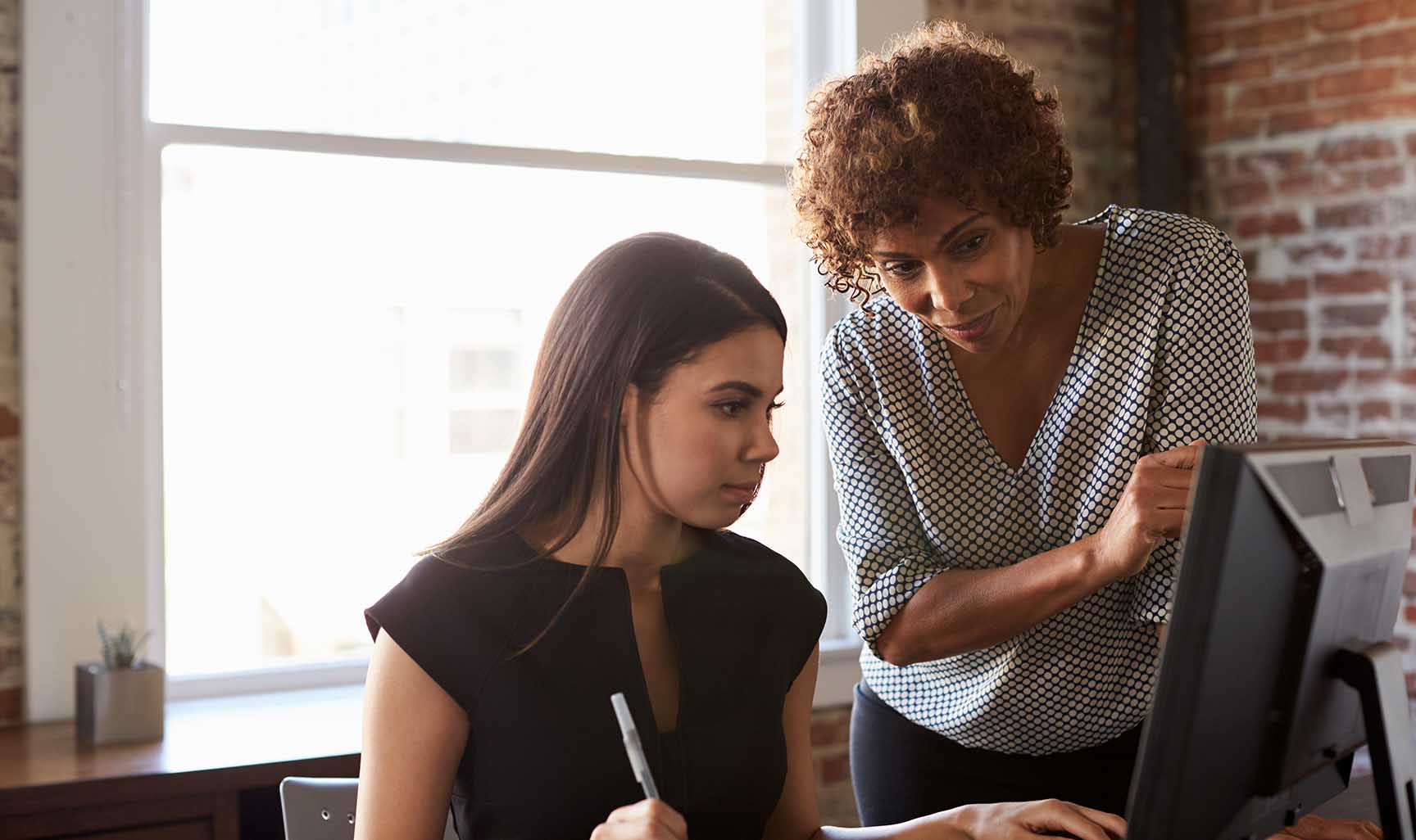 Person teaching someone how to something on a computer